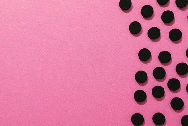 Geactiveerde houtskooltabletten op een roze achtergrond - Foto, afbeelding