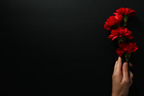 Flores en mano femenina sobre fondo negro, espacio para texto - Foto, imagen