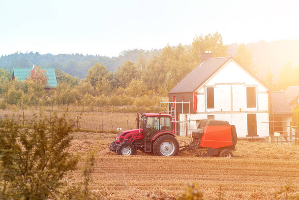 Traktor bestellt Felder bei Sonnenuntergang. Mähdrescher bei der Arbeit. Industrielle Landwirtschaft. Goldene Stunde der Landwirtschaft. - Foto, Bild