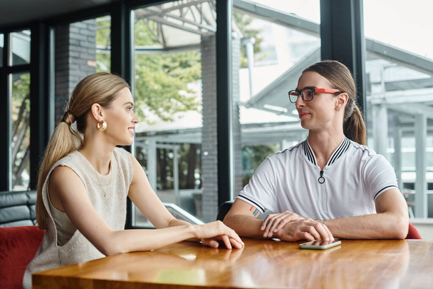 jonge collega 's man en vrouw chatten en kijken elkaar aan met glazen achtergrond, coworking - Foto, afbeelding