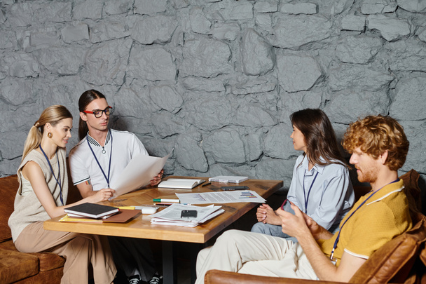 τέσσερις νέοι συνάδελφοι σε επιχειρήσεις casual ενδυμασία κάνει τα χαρτιά τους στο τραπέζι, έννοια της συνεργασίας - Φωτογραφία, εικόνα