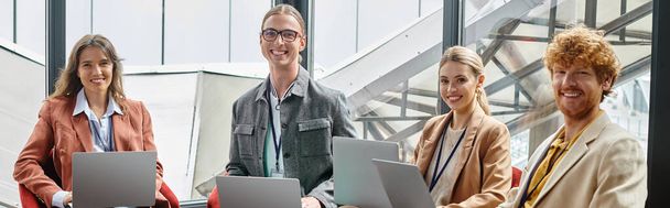 χαρούμενα νέα ομάδα σε smart casual φορούν κρατώντας φορητούς υπολογιστές και κοιτάζοντας κάμερα, coworking, banner - Φωτογραφία, εικόνα
