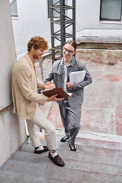 zwei junge Männer, die im Freien lächelnd ihren Papierkram, ihr Coworking-Konzept diskutieren - Foto, Bild