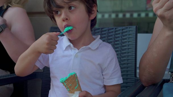 Piccolo ragazzo assaporando Blue Ice-Cream Cone con cucchiaio, bambino mangiare gelato colorato, colore blu dolce dessert cibo - Foto, immagini