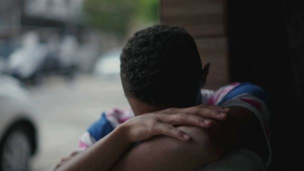 Один депрессивный молодой чернокожий мужчина борется с социальной изоляцией и психическими заболеваниями, покрывая лицо стыдом и сожалением. Человек афроамериканского происхождения сталкивается с тихим отчаянием - Фото, изображение