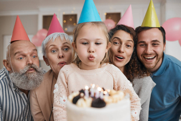 Születésnapi torta, gyertyák és nagy család ünnepelnek egy otthoni party, esemény és a boldogság az arcon egy házban együtt. Anya, apa és nagyszülők izgatottan várják a meglepetés összejövetelt gyerekekkel vagy gyerekekkel.. - Fotó, kép