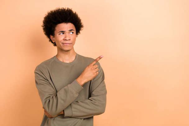 Photo of thoughtful minded confused guy afro hairdo wear khaki shirt look directing empty space isolated on beige color background. - Photo, Image