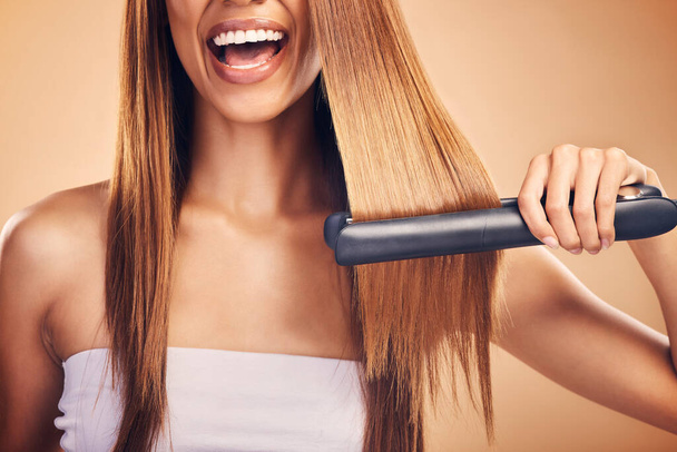 Hand, hair straightener and woman in studio for beauty, cosmetics or appliance. Happy person on brown background for heat treatment, healthy results and hairdresser or salon flat iron on texture. - Photo, Image