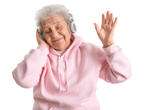 Seniorin mit Kopfhörer hört Musik auf weißem Hintergrund - Foto, Bild