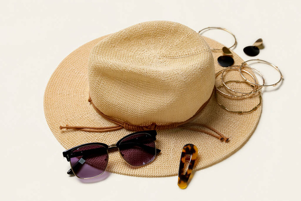 Κομψό κόσμημα με γυαλιά ηλίου και καλοκαιρινό καπέλο σε ελαφρύ φόντο - Φωτογραφία, εικόνα