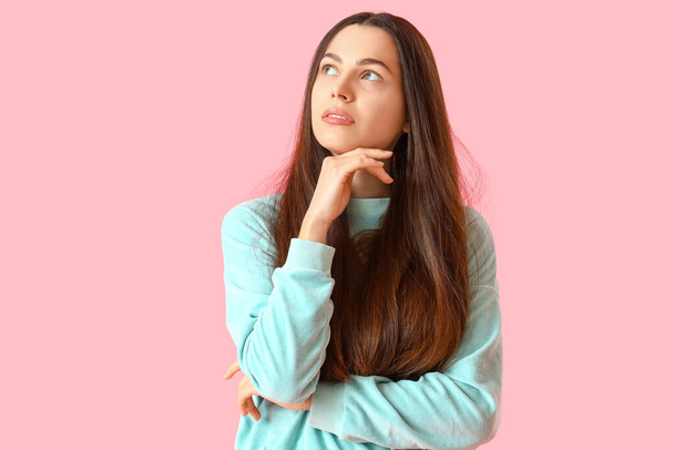Gondolkodó fiatal nő rózsaszín háttér - Fotó, kép