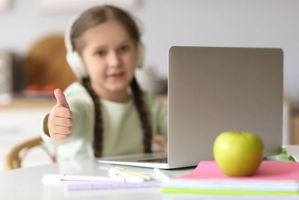 Pieni tyttö kuulokkeet kannettava tietokone opiskelee tietotekniikkaa verkossa kotona - Valokuva, kuva