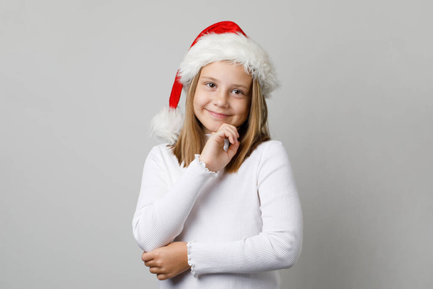 Aranyos karácsonyi gyerek kislány a Mikulás kalap mosolygós fehér háttér, Xmas portré - Fotó, kép
