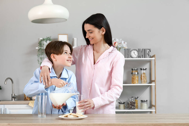 Μικρό αγόρι και η μητέρα του ρίχνει φρέσκο γάλα στην κουζίνα - Φωτογραφία, εικόνα