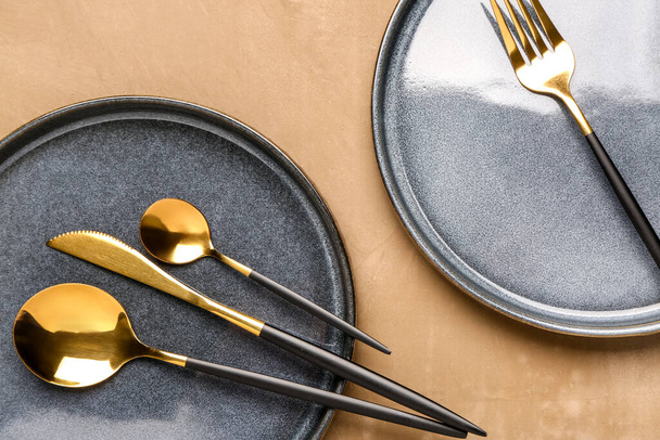 Piatti puliti con set di posate dorate sul tavolo marrone - Foto, immagini