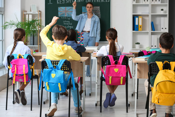 Pequeños alumnos con mochilas que tienen clase en el aula, vista trasera - Foto, Imagen