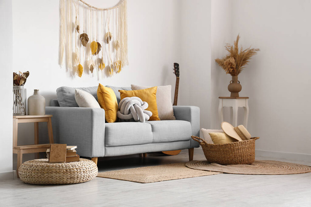 Интерьер светлой гостиной с диваном и плетеной корзиной - Фото, изображение