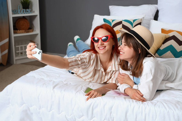 Les jeunes femmes prennent selfie tout en déballant la valise dans la chambre - Photo, image