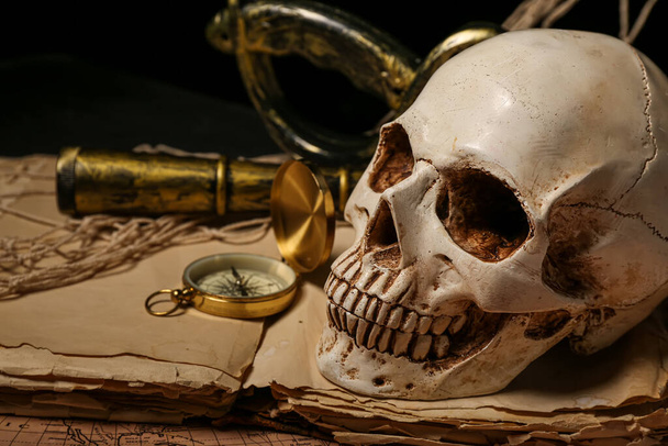Ludzka czaszka z lunetą, stare rękopisy, mapa świata i kompas na czarnym tle - Zdjęcie, obraz