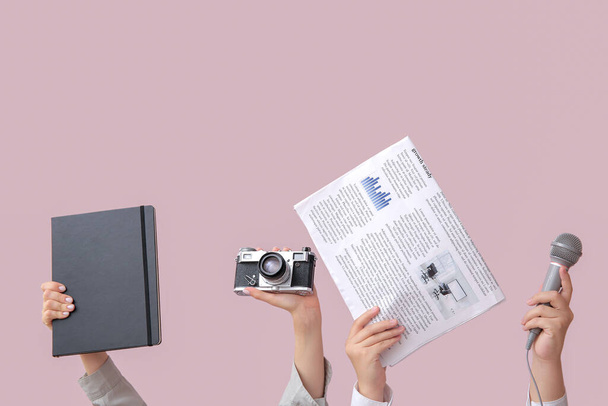 Female hands with newspaper, notebook, microphone and photo camera on color background - Photo, Image