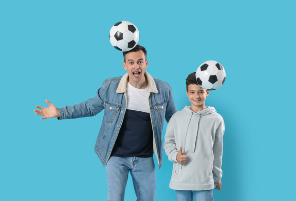 Kleiner Junge und sein Vater spielen mit Fußballbällen auf blauem Hintergrund - Foto, Bild