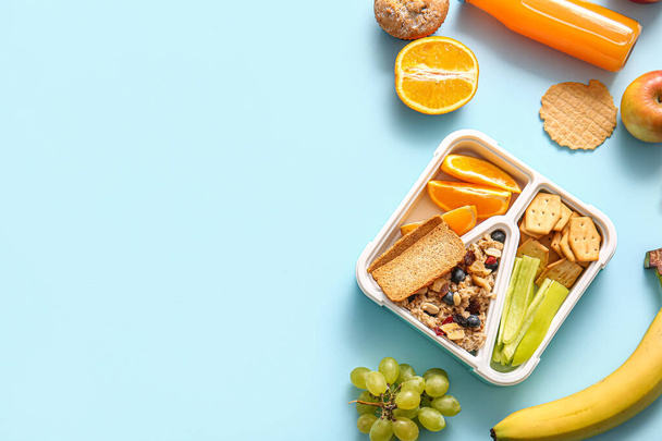 Lunchbox with delicious food and bottle of juice on blue background - Photo, Image