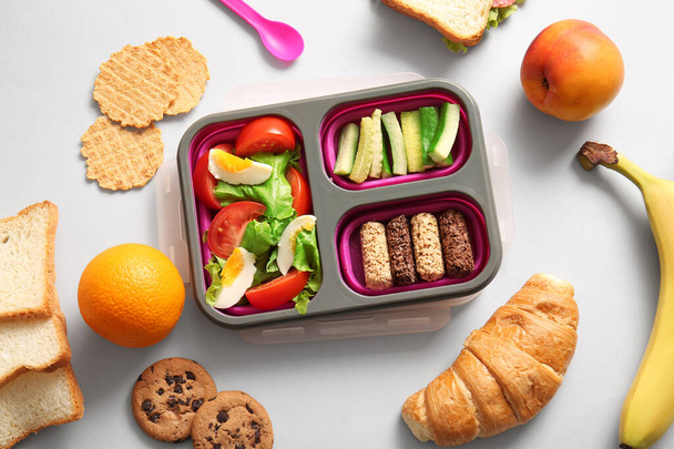 Lunchbox met verschillende heerlijke gerechten op witte achtergrond - Foto, afbeelding