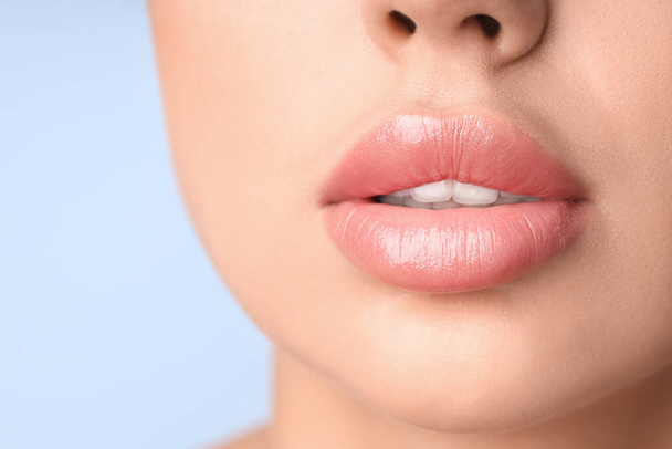 Young woman with beautiful lips on blue background, closeup - Photo, Image
