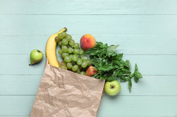 Saco de papel cheio de frutas frescas e ervas em fundo de madeira verde - Foto, Imagem