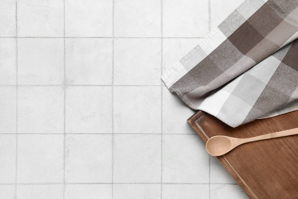 Placa de madeira com colher e guardanapo na mesa de cozinha de azulejo branco - Foto, Imagem