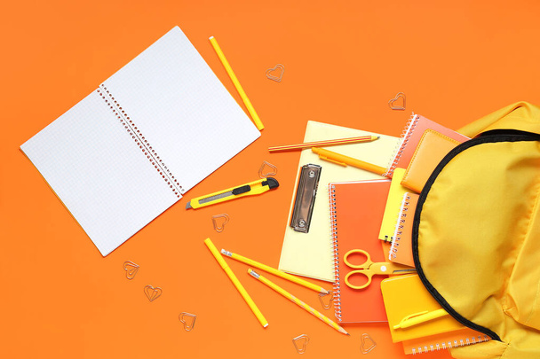 Κομψή σχολική τσάντα πλάτης και διάφορα χαρτικά σε πορτοκαλί φόντο - Φωτογραφία, εικόνα