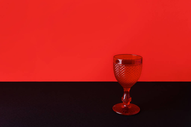 Weinglas auf doppeltem rot-schwarzem Hintergrund. Halloween Black Friday Verkaufskonzept mit Kopierraum - Foto, Bild