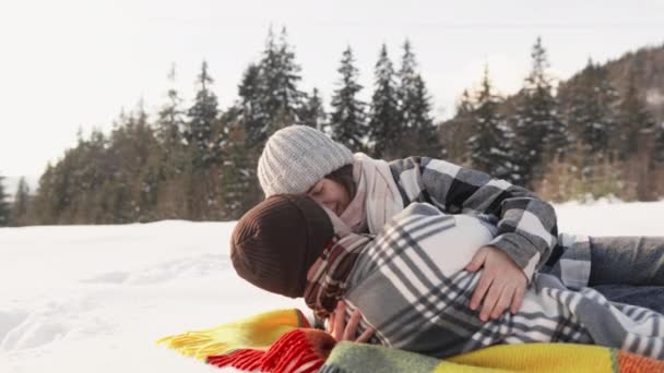 Die schneebedeckte Landschaft trägt zur Atmosphäre der Entspannung und des Vergnügens bei, wenn das Brautpaar Zeit auf der Decke verbringt. Zärtlichkeit und Spaß trennen ein Paar auf einer Decke, das die Erholung im Freien bevorzugt. - Filmmaterial, Video