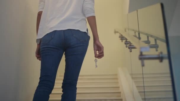 Zblízka zaostřit ženskou ruku drží klíč od nového domova na schodišti - Záběry, video