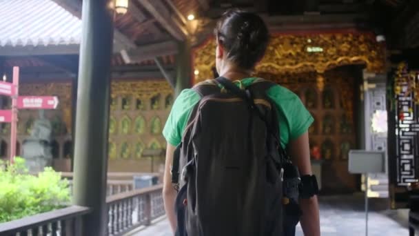 40-летняя женщина с рюкзаком прогуливается по юго-восточному азиатскому храму, захватывая культуру и расширение прав и возможностей  - Кадры, видео