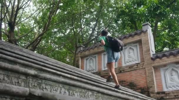 40-vuotias nainen, jolla on reppu kävelemässä Kaakkois-Aasian temppelin läpi, vangitsemassa kulttuuria ja voimaannuttamista  - Materiaali, video