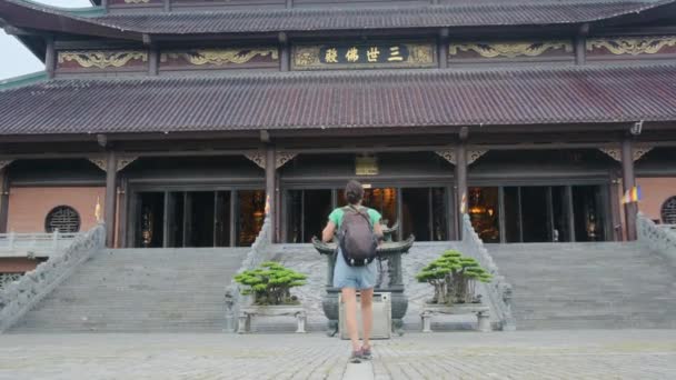 40-jarige vrouw met rugzak wandelen door Zuidoost-Aziatische tempel, het vastleggen van cultuur en empowerment  - Video