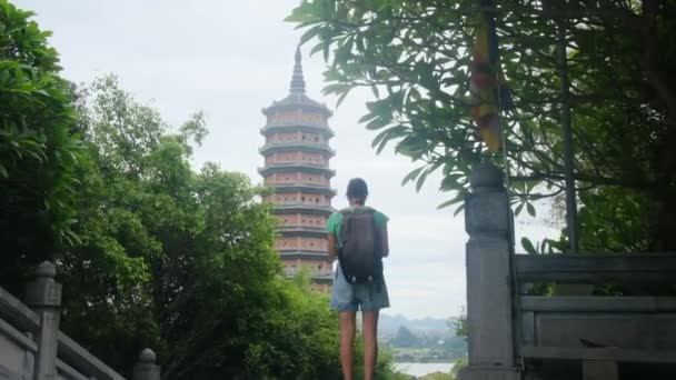 Mujer de 40 años con mochila caminando por el templo del sudeste asiático, capturando la cultura y el empoderamiento  - Metraje, vídeo