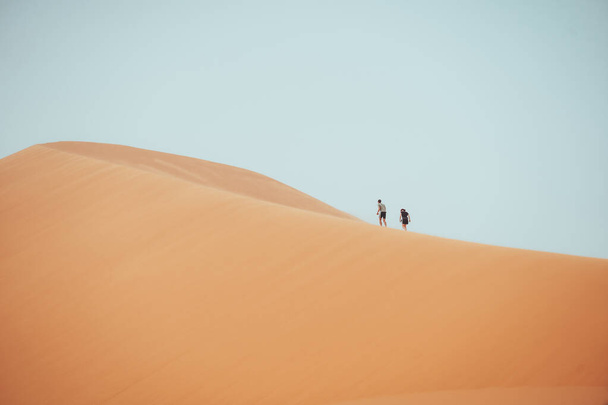 Люди карабкаются по дюнам Эрг Чебби в пустыне Сахара, Мерзуга, Марокко. Высокое качество фото - Фото, изображение