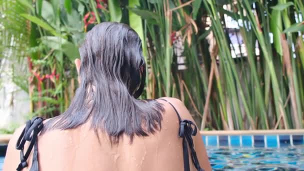 Вид сзади Молодая женщина расслабляется в бассейне - Кадры, видео