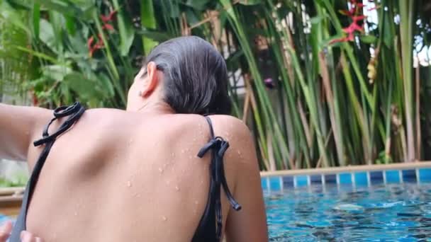 Πίσω όψη της νεαρής γυναίκας χαλαρώνοντας στην πισίνα - Πλάνα, βίντεο