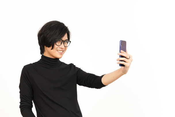 Prendre un selfie en utilisant Smartphone de bel homme asiatique isolé sur fond blanc - Photo, image