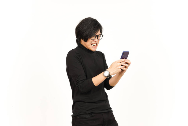Tenue et utilisation Smartphone avec le visage en colère de bel homme asiatique isolé sur fond blanc - Photo, image