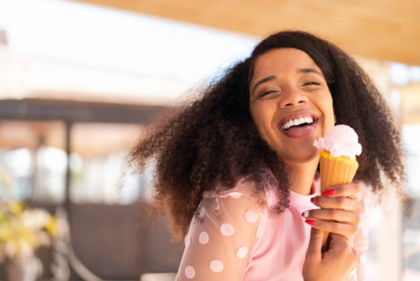 Joven mujer afroamericana con un helado de corneta al aire libre - Foto, imagen