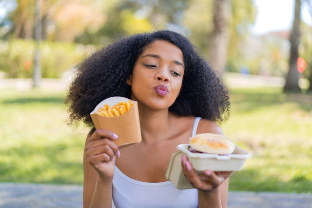 Fiatal afro-amerikai nő a szabadban kezében egy burger és sült chips - Fotó, kép