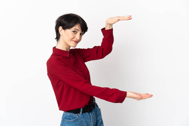 Frau mit kurzen Haaren isoliert auf weißem Hintergrund hält Copyspace, um eine Anzeige einzufügen - Foto, Bild