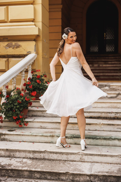 Vue arrière d'une magnifique mariée dans une belle robe de mariée blanche s'amuser et danser en plein air le jour de son mariage. - Photo, image