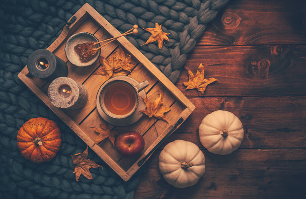 Herfst stemmingsconcept. Warm, gezellig en rustiek stilleven met kopje thee, kaarsen en pompoenen. - Foto, afbeelding