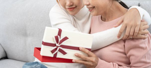 Festa della mamma, carina ragazza adolescente asiatica dare confezione regalo per matura mamma di mezza età. Amore, bacio, cura, sorriso felice godersi il tempo in famiglia. festeggiando l'occasione speciale, buon compleanno, felice anno nuovo, buon Natale - Foto, immagini