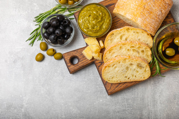 Ciabatta ja oliivit. Tuore italialainen ciabatta-leipä yrtteillä, oliiviöljyllä, parmesaanilla ja pestokastikkeella, oliivit puupohjalla, ylhäältä katsottuna, kopiointiväli. Tekstipaikka. kopioi tila. - Valokuva, kuva